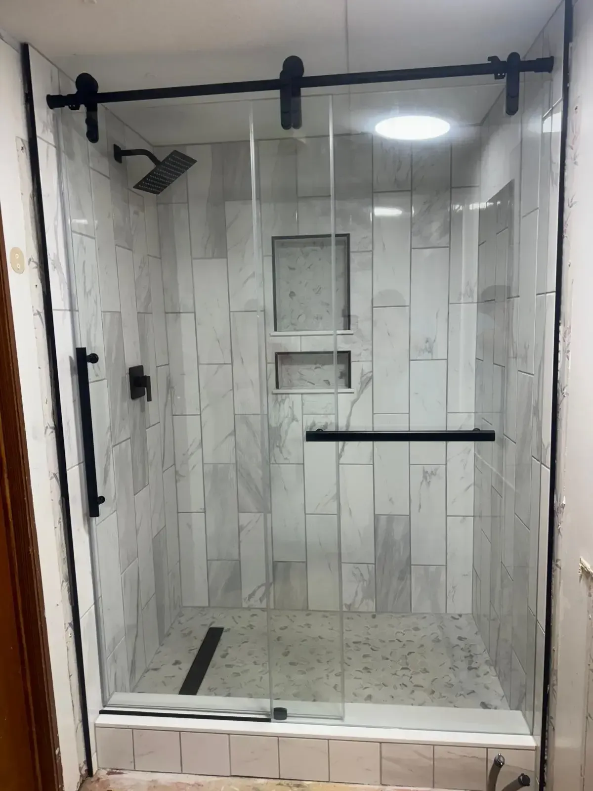 A bathroom with a sliding glass shower door and marble tiles.