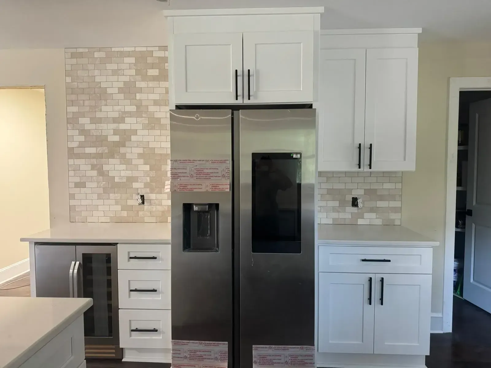 A kitchen with white cabinets and a stainless steel refrigerator