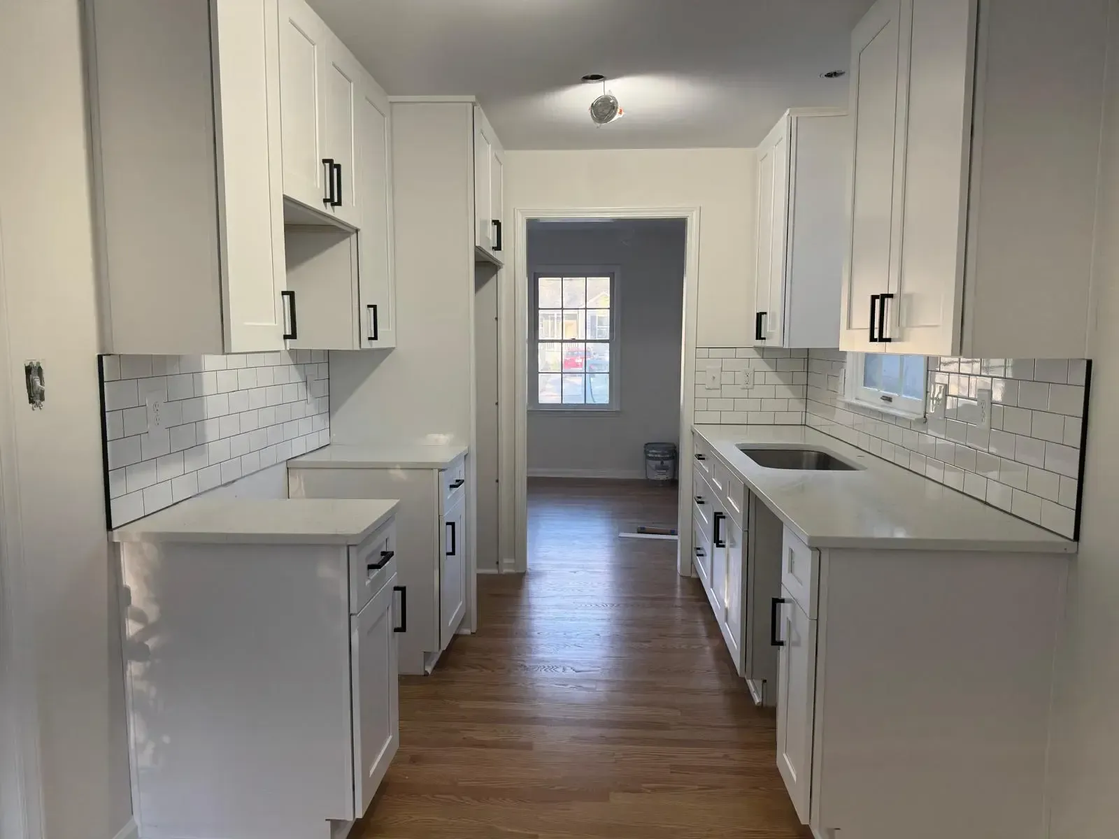 A kitchen with white cabinets and a sink in a house.