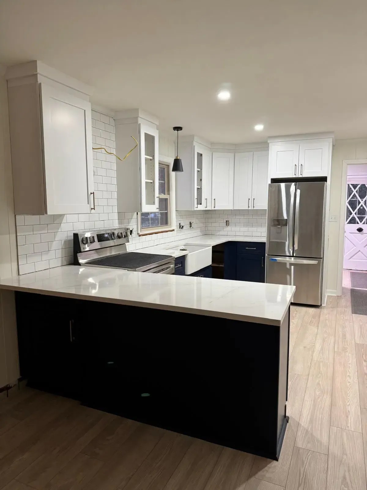 A kitchen with white cabinets , black cabinets , stainless steel appliances , and a large island.