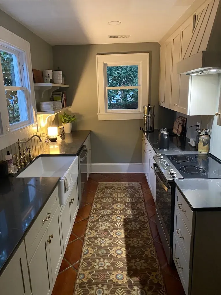 A kitchen with a sink , stove , and window.