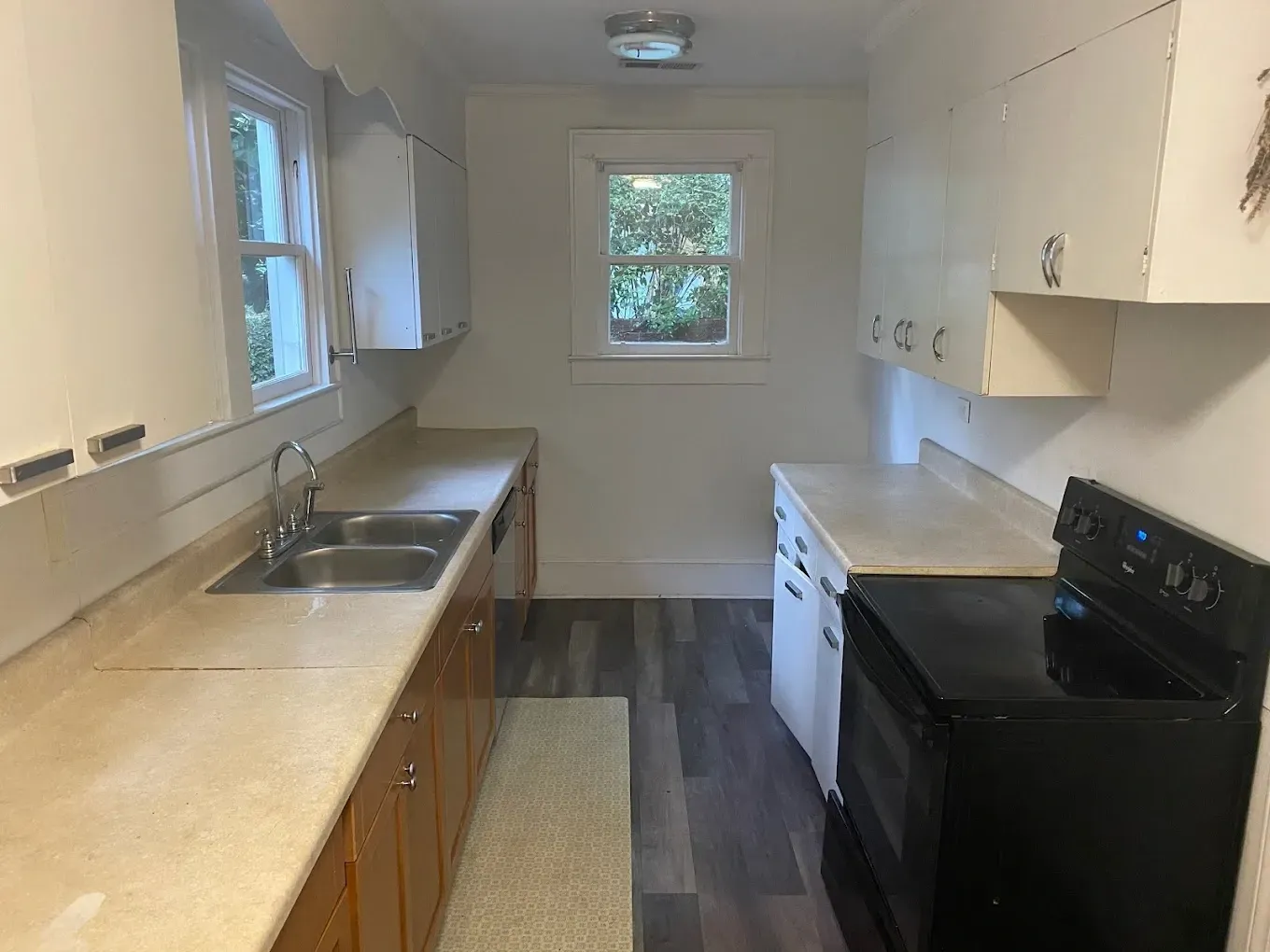 A kitchen with a stove , sink , cabinets and a window.