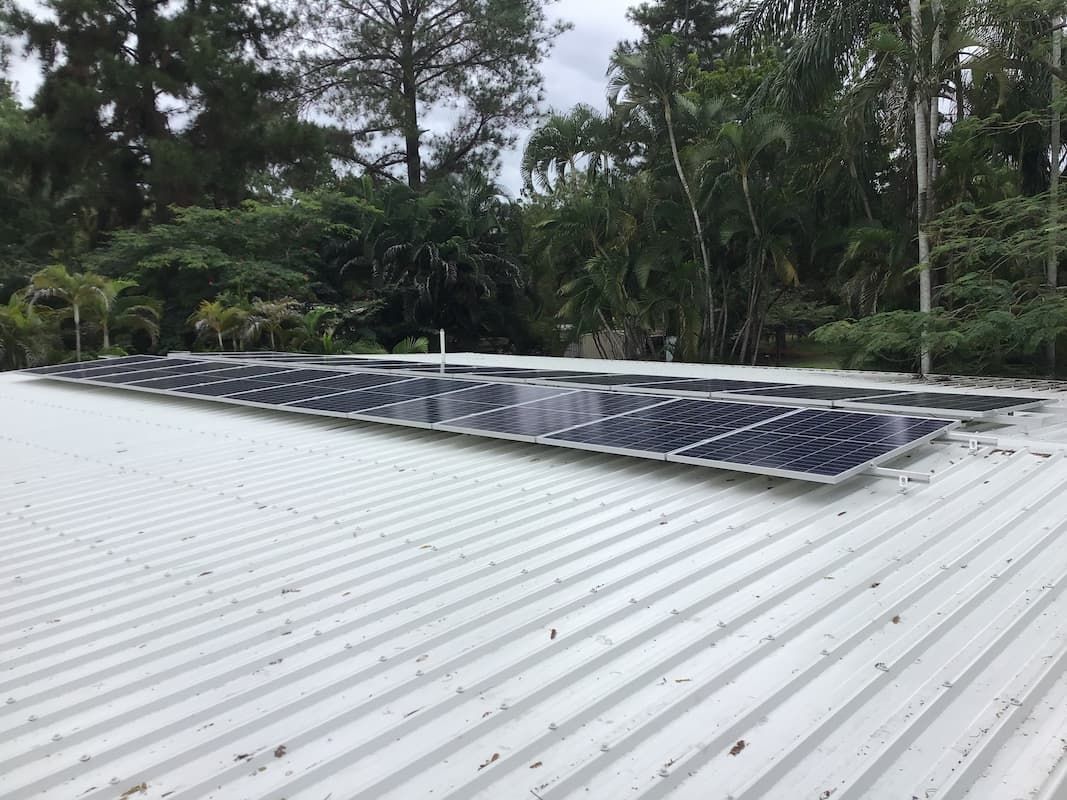 A Row of Solar Panels Are Sitting on Top of A White Roof — Central Solar Services in Garbutt, QLD