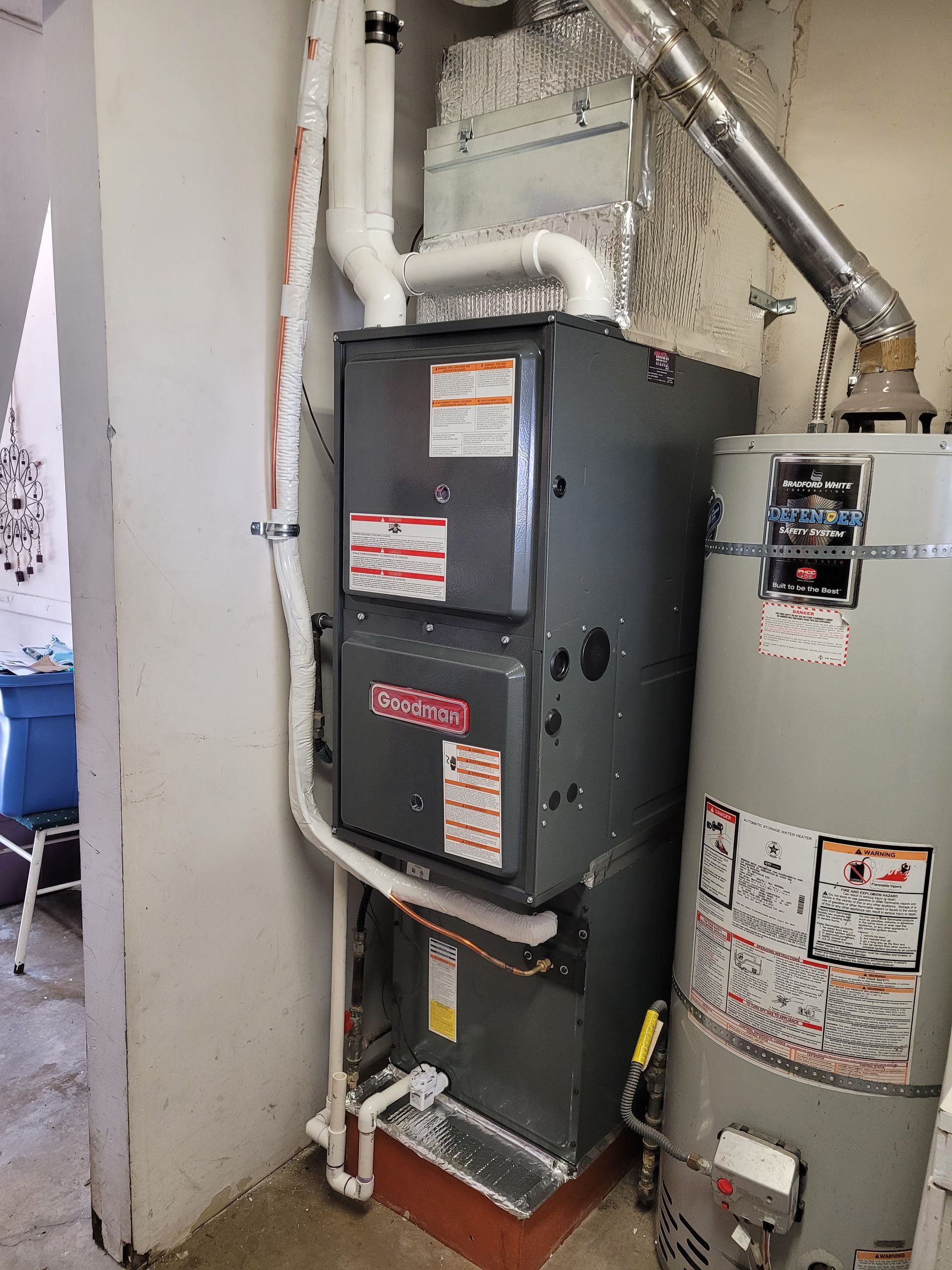 a furnace and a water heater are sitting next to each other in a room .