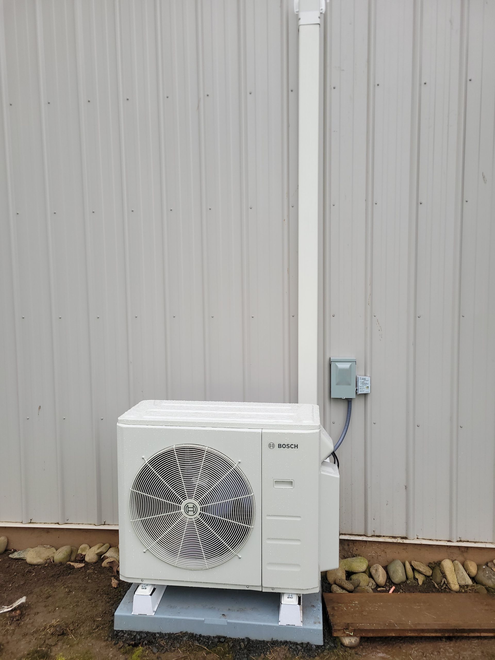 a white air conditioner is sitting outside of a building .