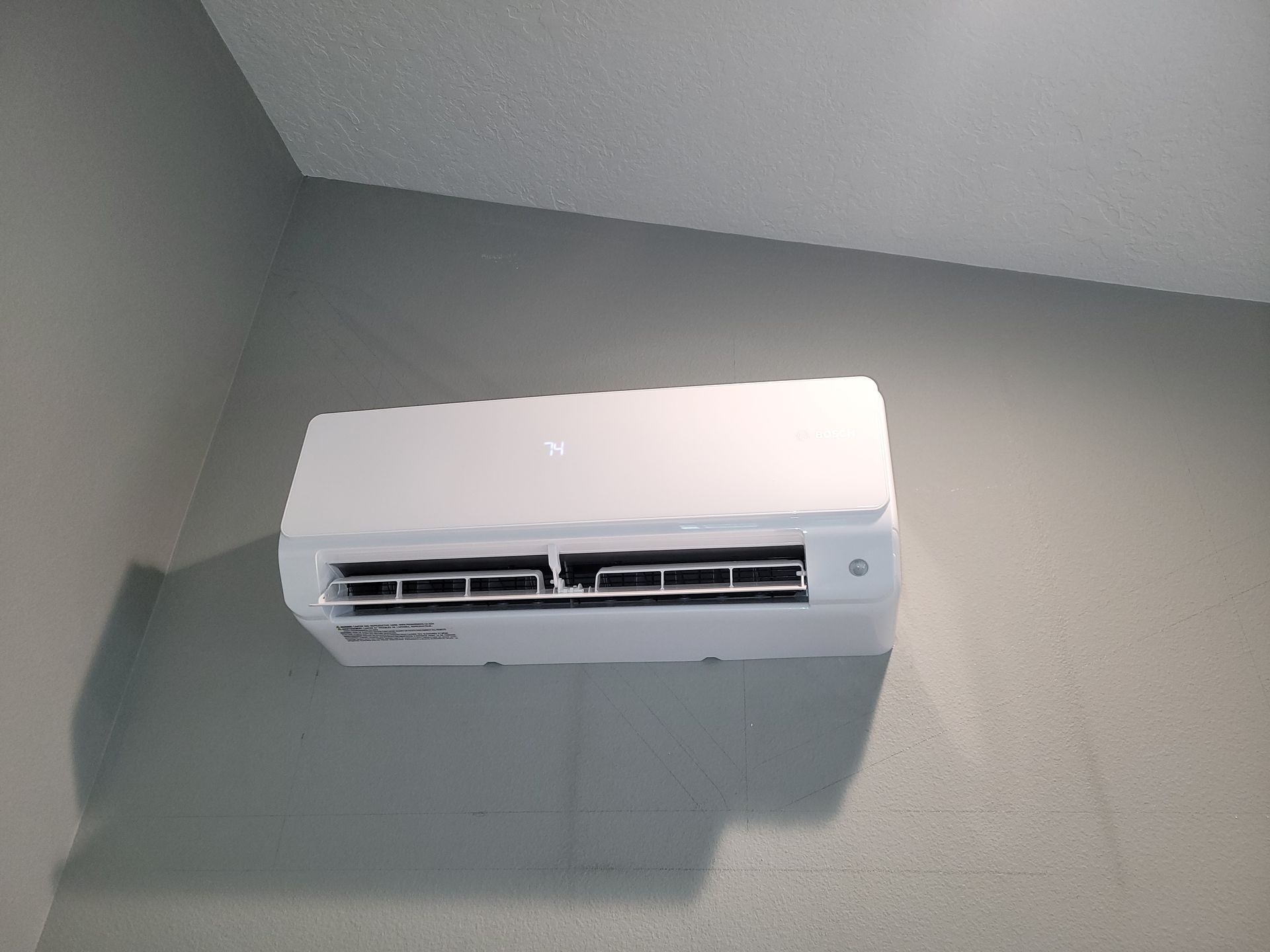 a white air conditioner is hanging on a wall in a room .
