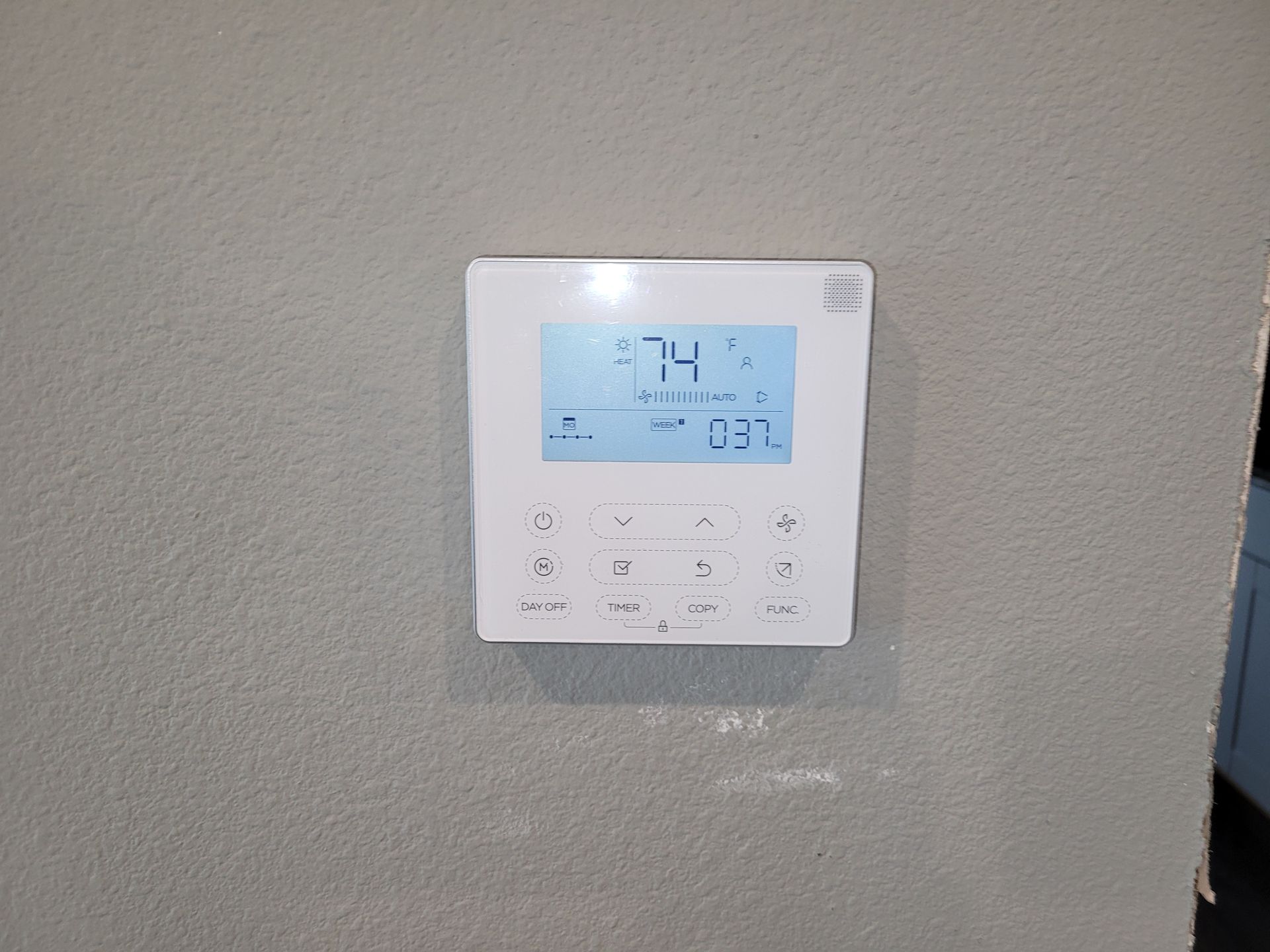 a white thermostat is hanging on a white wall .