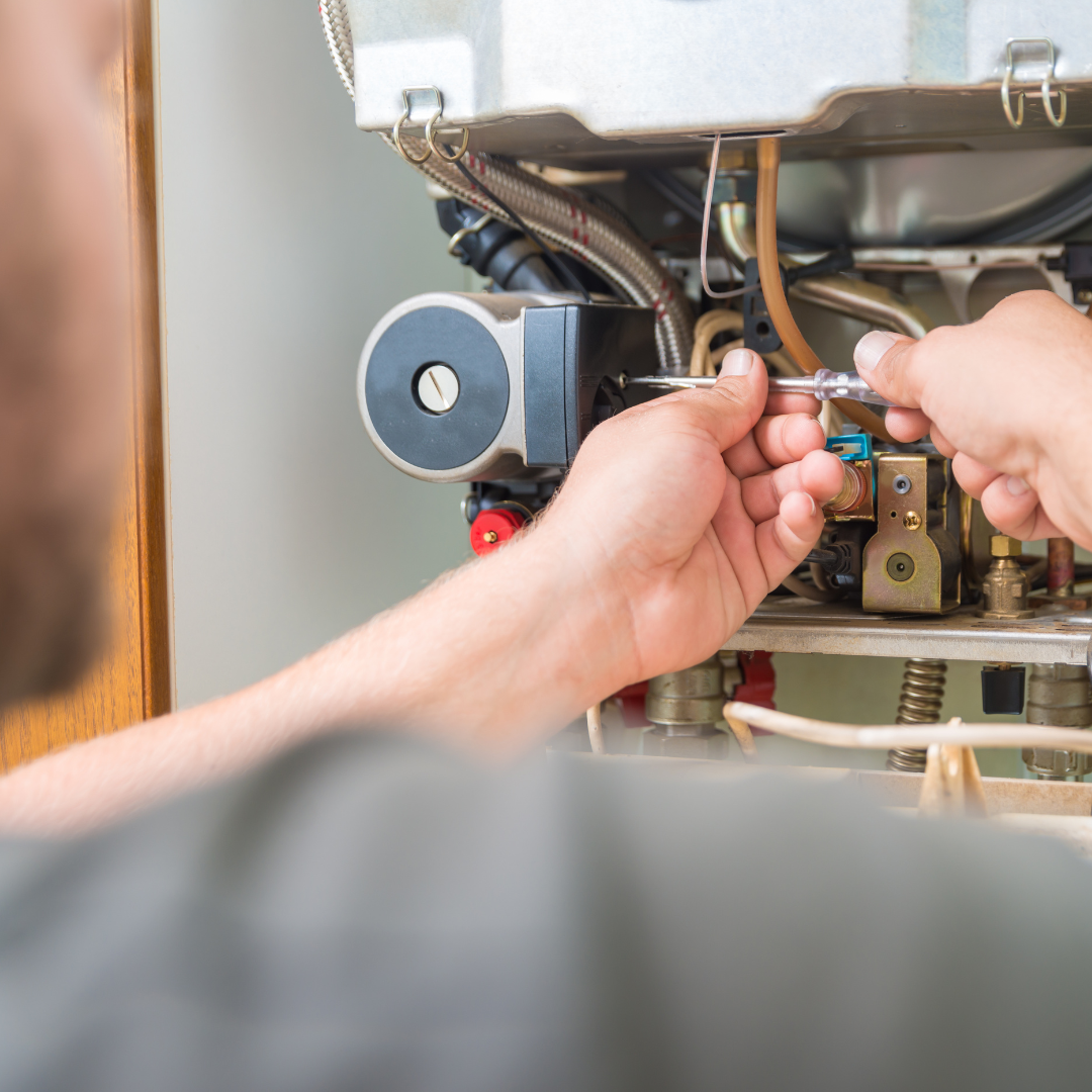 Person repairing a heating system with a wrench in a utility room.