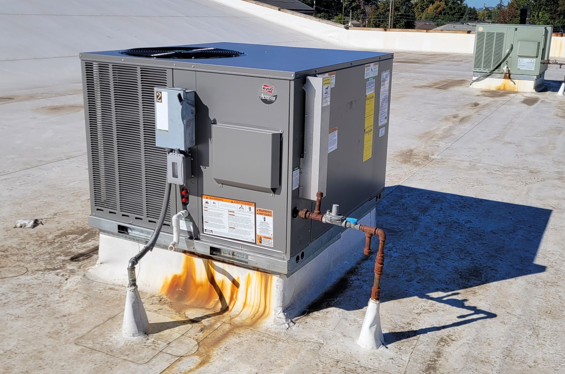 Rooftop air conditioning unit with orange staining on its base.