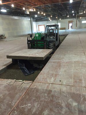 a forklift is sitting on top of a large concrete slab in a warehouse .