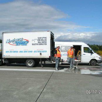 a white van is parked next to a white truck on the side of the road .