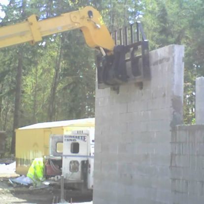 a yellow crane is lifting a brick wall