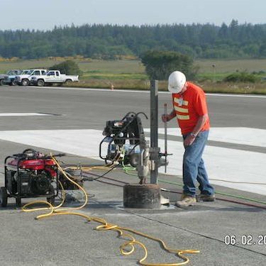 a man in an orange shirt is working on a machine on a runway .