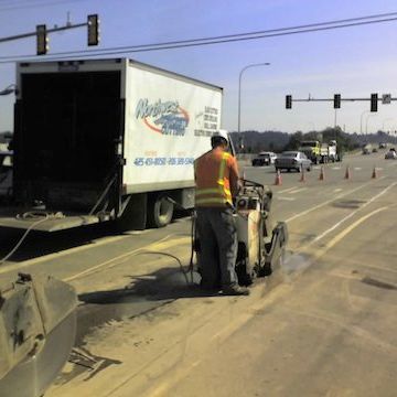 a man is using a machine to cut a hole in the road