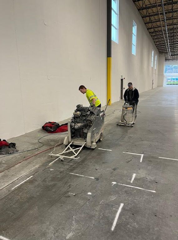 two men are working on a machine in a large warehouse .