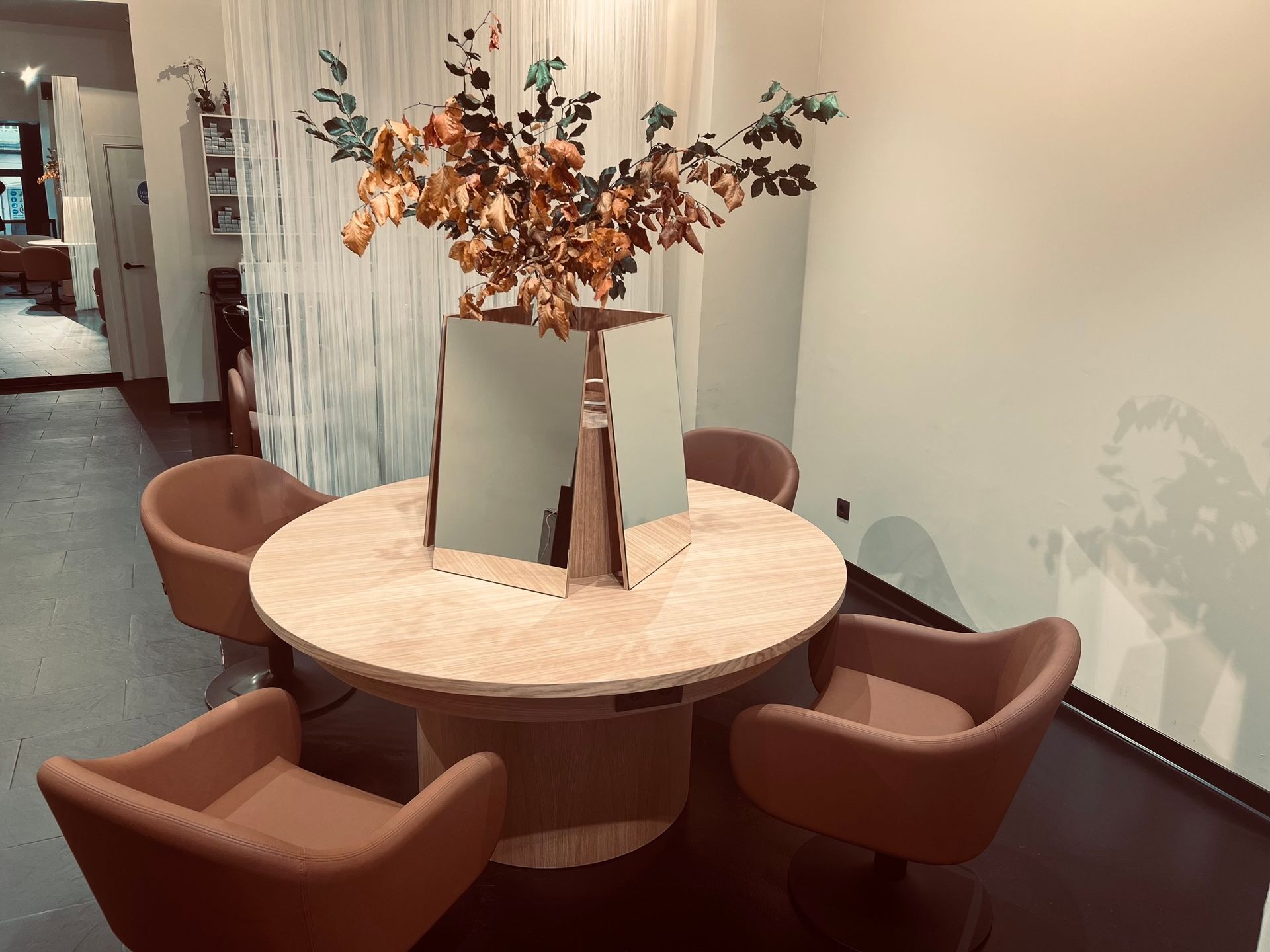 Una habitación con una mesa redonda y sillas y un jarrón con flores encima.