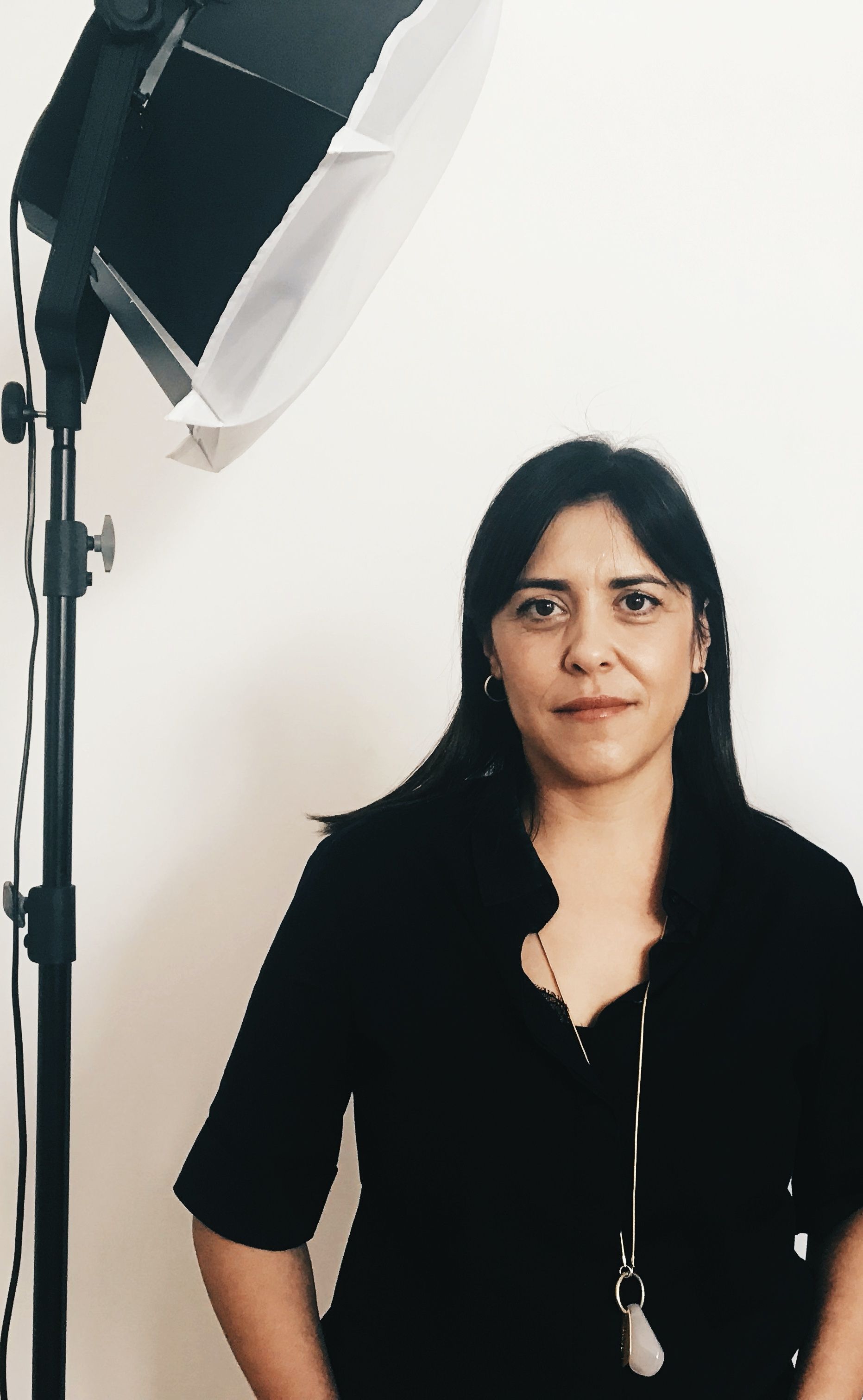 Una mujer con una camisa negra está parada frente a una luz.