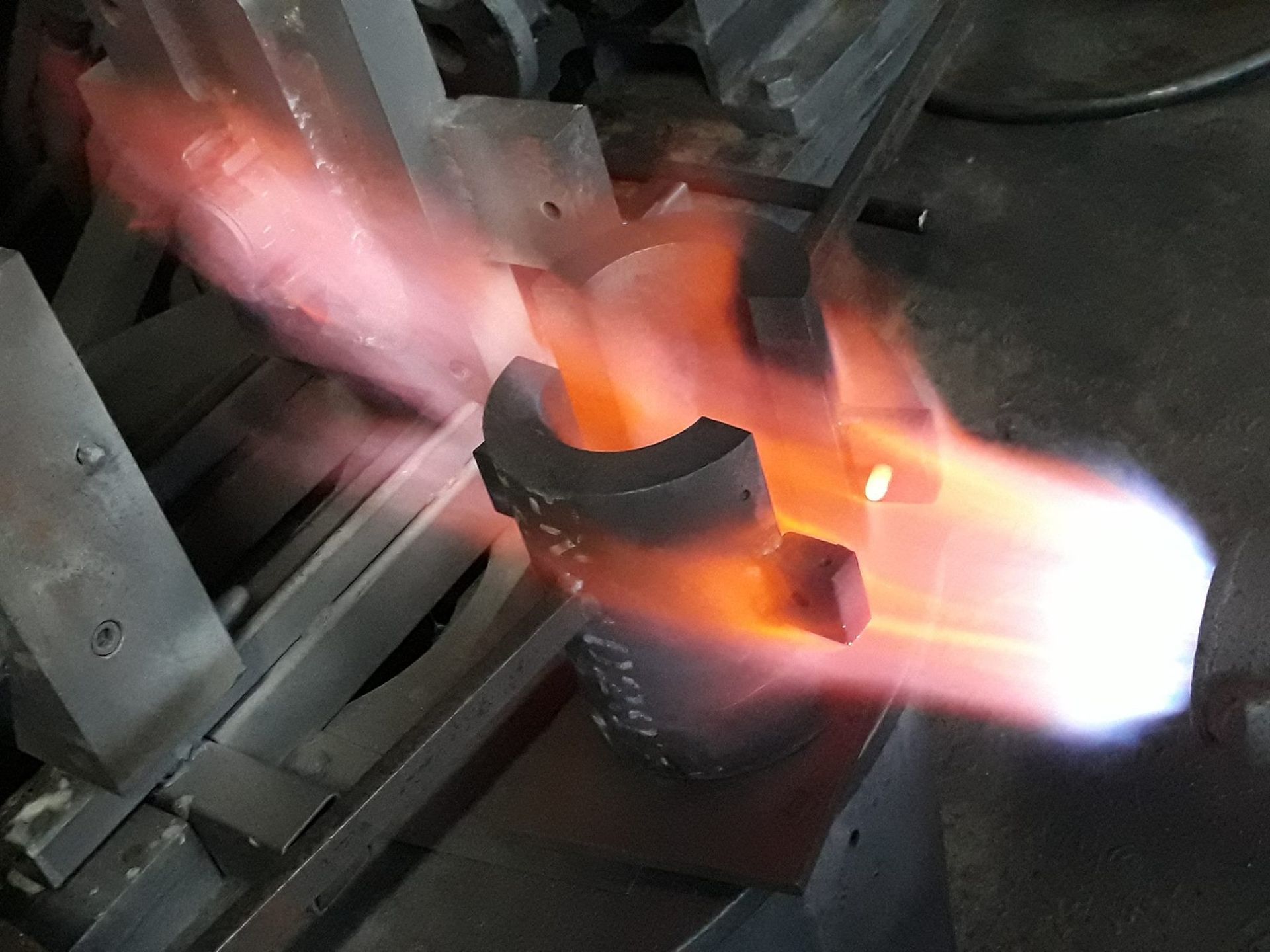 Acciaio rosso fuso che fuoriesce dal beccuccio di una fornace, risplendendo intensamente.