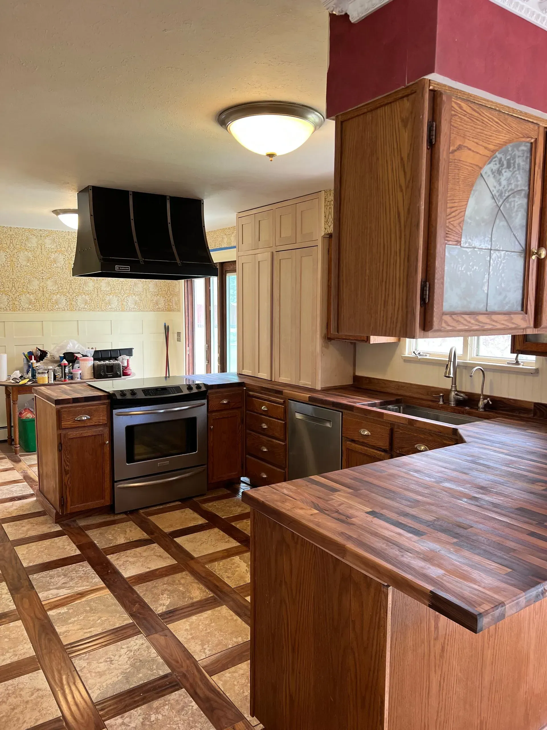 Modern kitchen with gray countertops, white cabinets, wood accent wall, black appliances, and a hallway entrance.