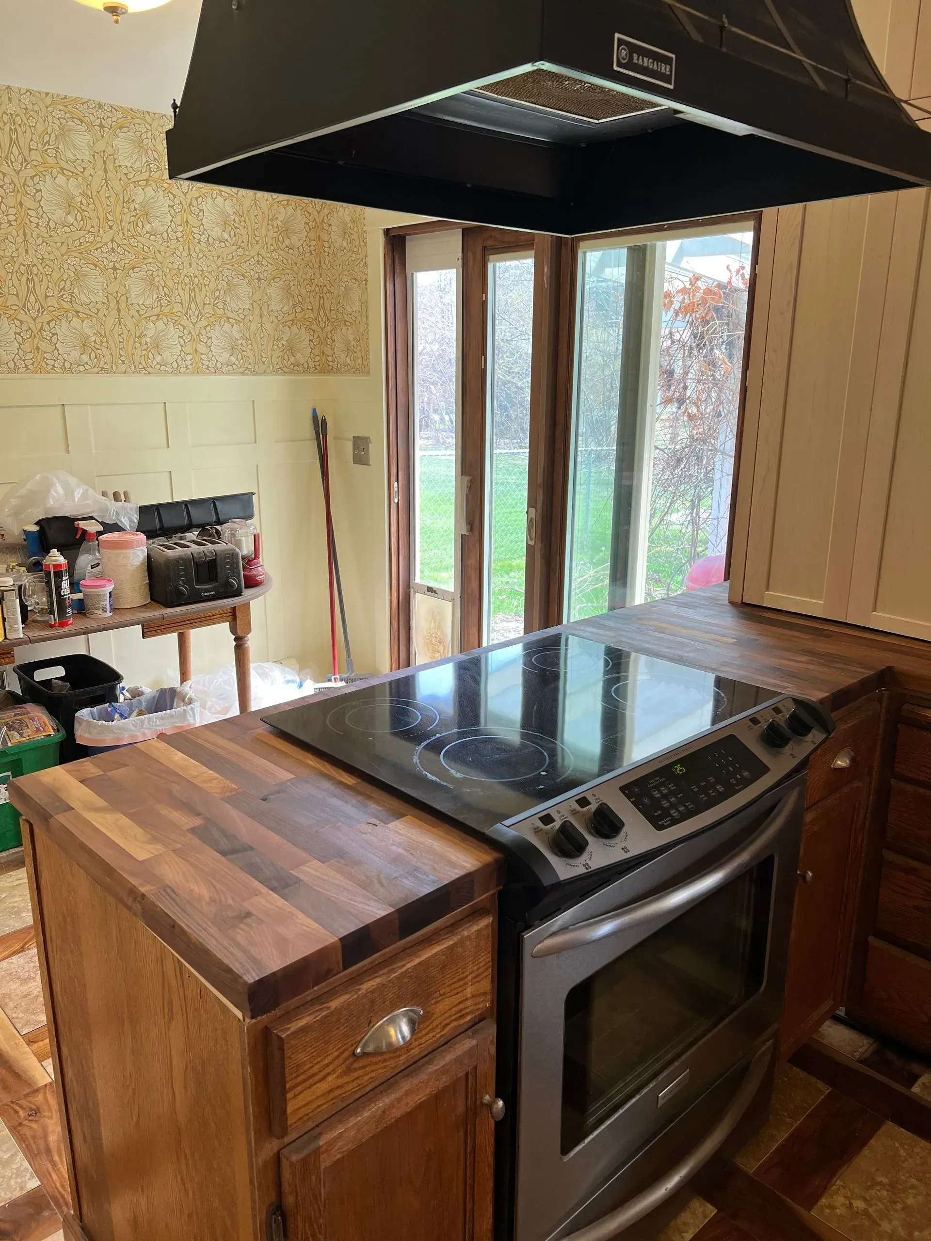 Gray kitchen cabinets and countertops in a modern kitchen with built-in ovens and range hood.