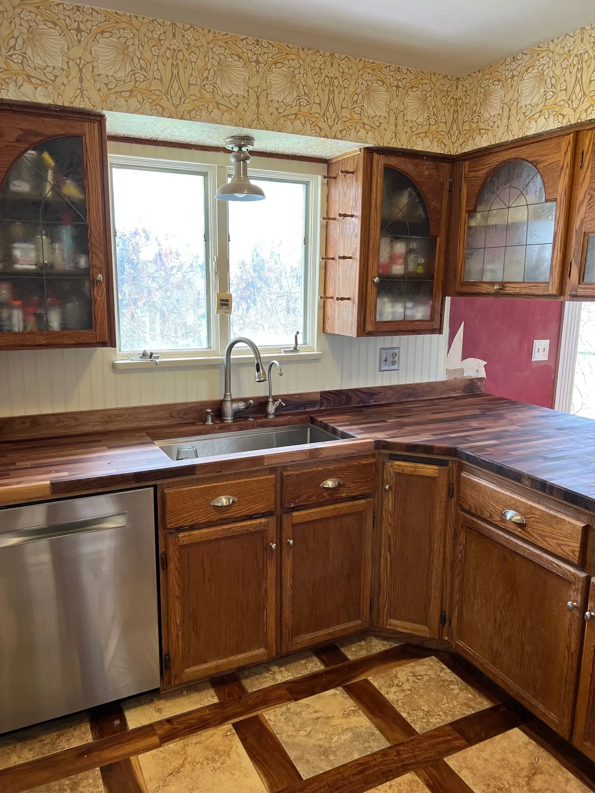 Bright white kitchen with granite countertops, stainless steel appliances, and two windows.
