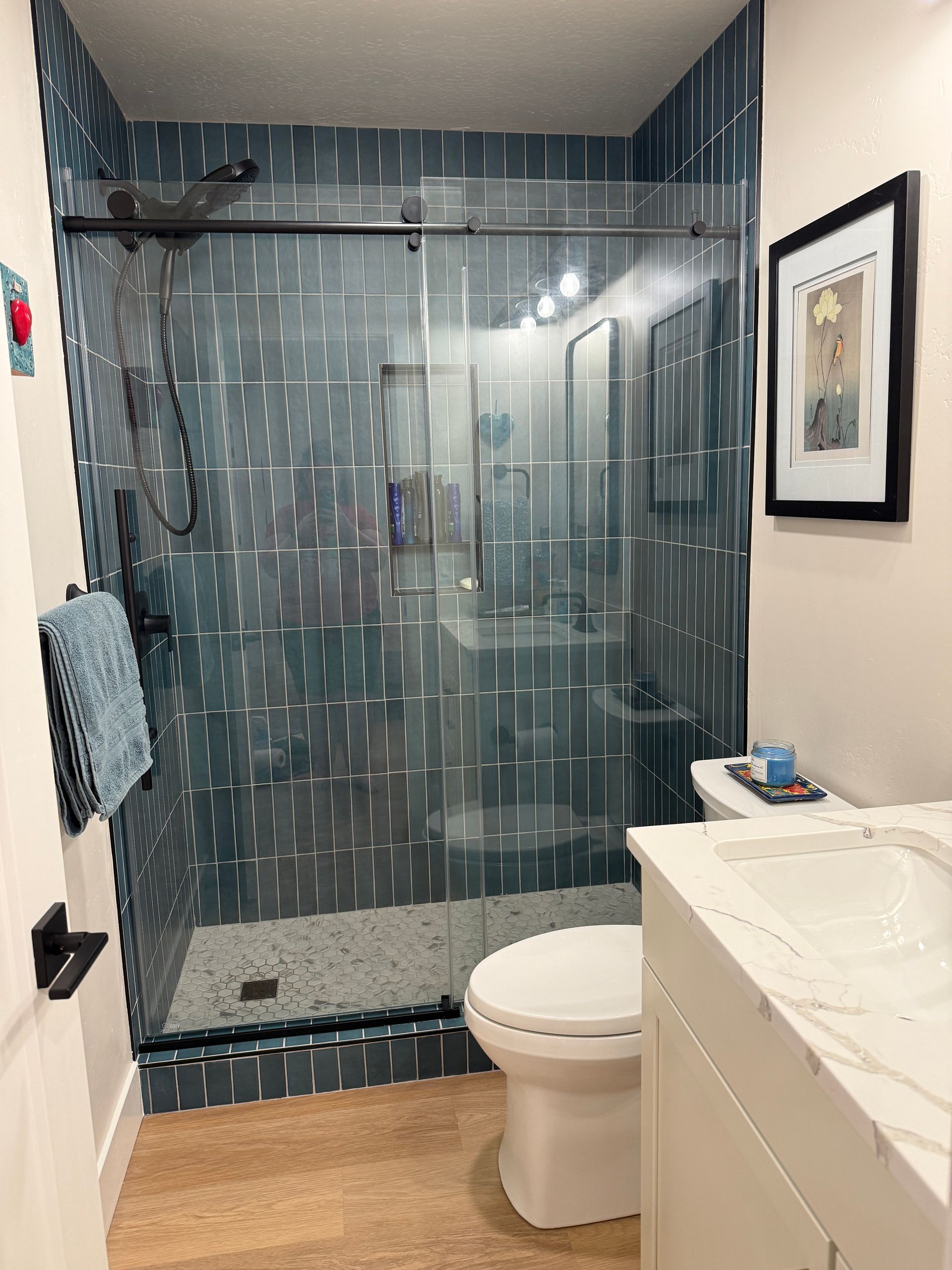 Wooden deck extension with brown composite boards, set on gravel, next to a house with trees in the background.
