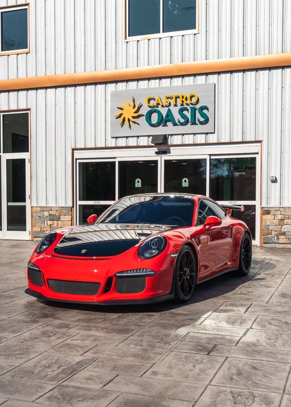 A red Porsche 911 GT3 parked in front of a building with a 