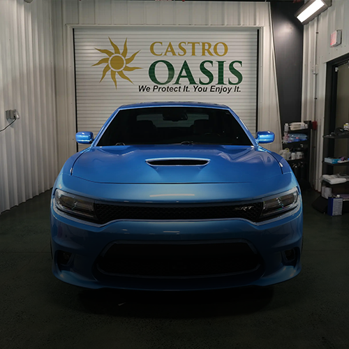 A bright blue Dodge Charger parked in a garage with a 