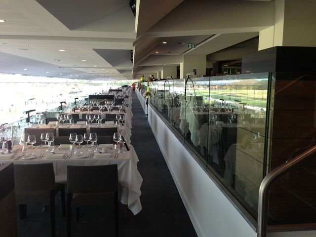 A long hallway with tables and chairs and a glass wall
