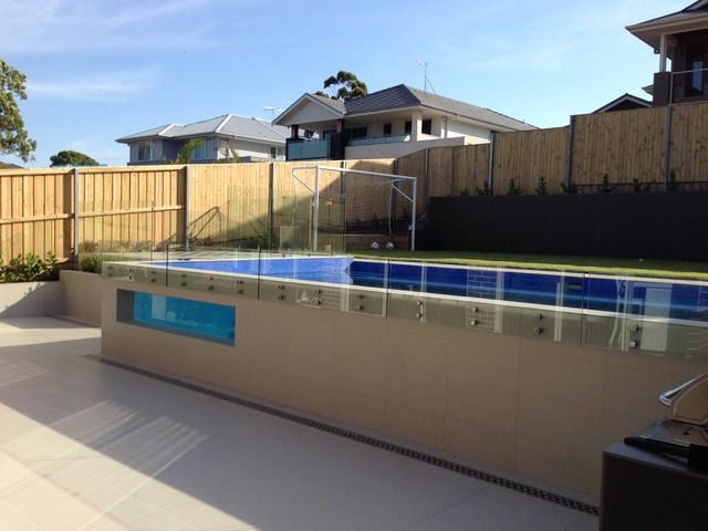 A large swimming pool with a glass fence around it