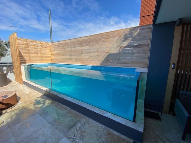 A large swimming pool is surrounded by a wooden fence.