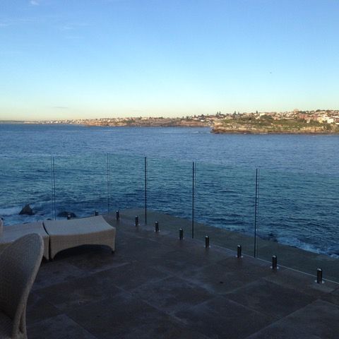 A view of the ocean from a balcony with a glass railing.