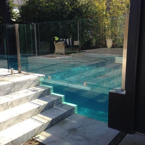 A swimming pool with a glass fence and stairs leading to it