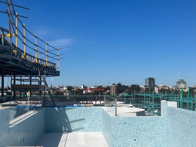 A swimming pool under construction with a city in the background