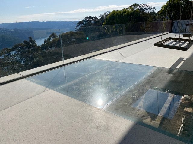 A balcony with a glass railing overlooking a body of water