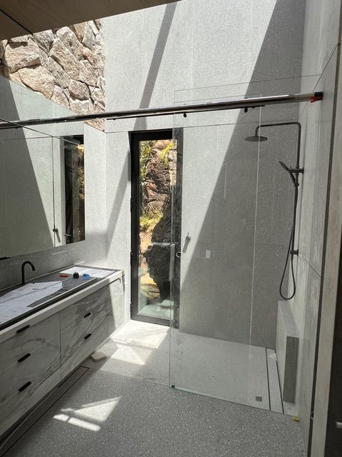 A bathroom with a walk in shower and a sink