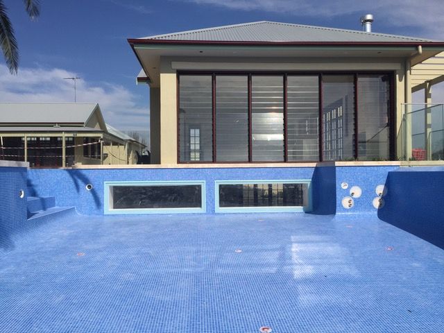 An empty swimming pool with a house in the background.