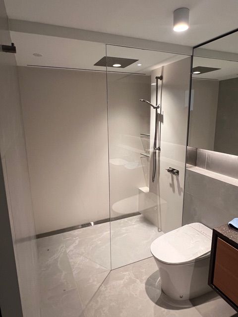 A bathroom with a toilet , shower and mirror.