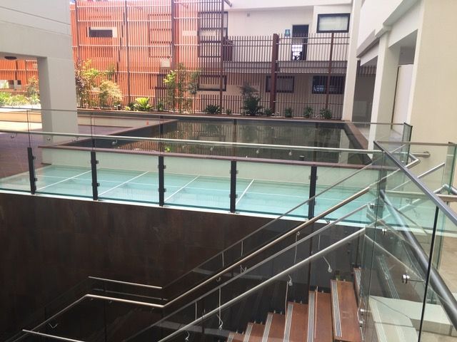 A staircase with a glass railing and a pool in the background