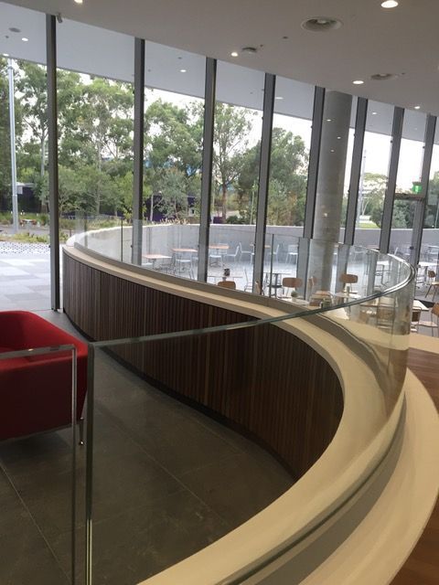 A curved staircase with a glass railing and a red chair