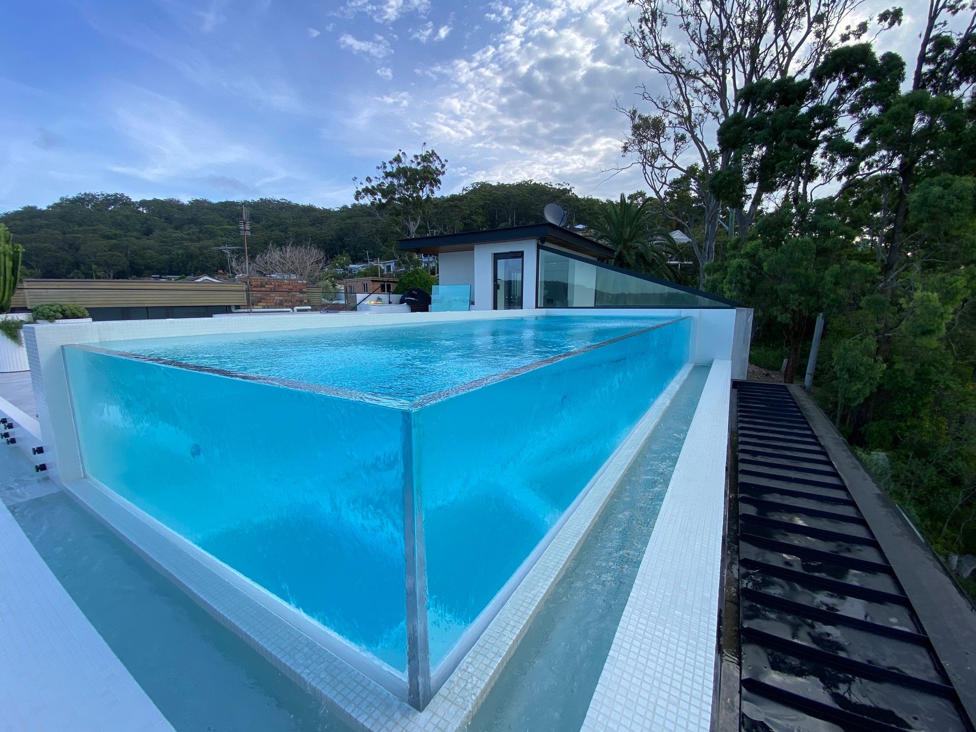 A large swimming pool with a clear glass fence surrounding it.