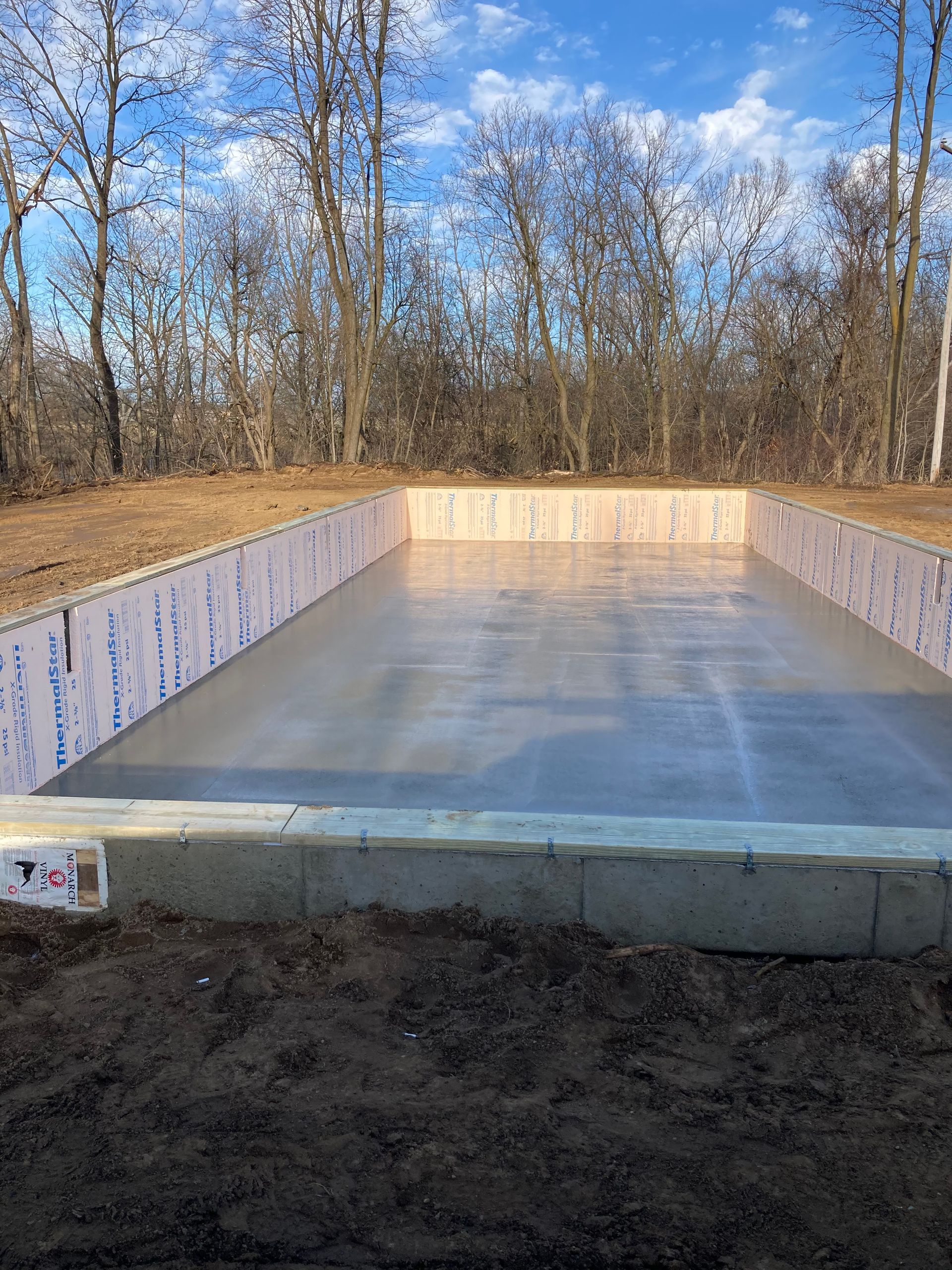 A large concrete slab is sitting in the middle of a dirt field with trees in the background.