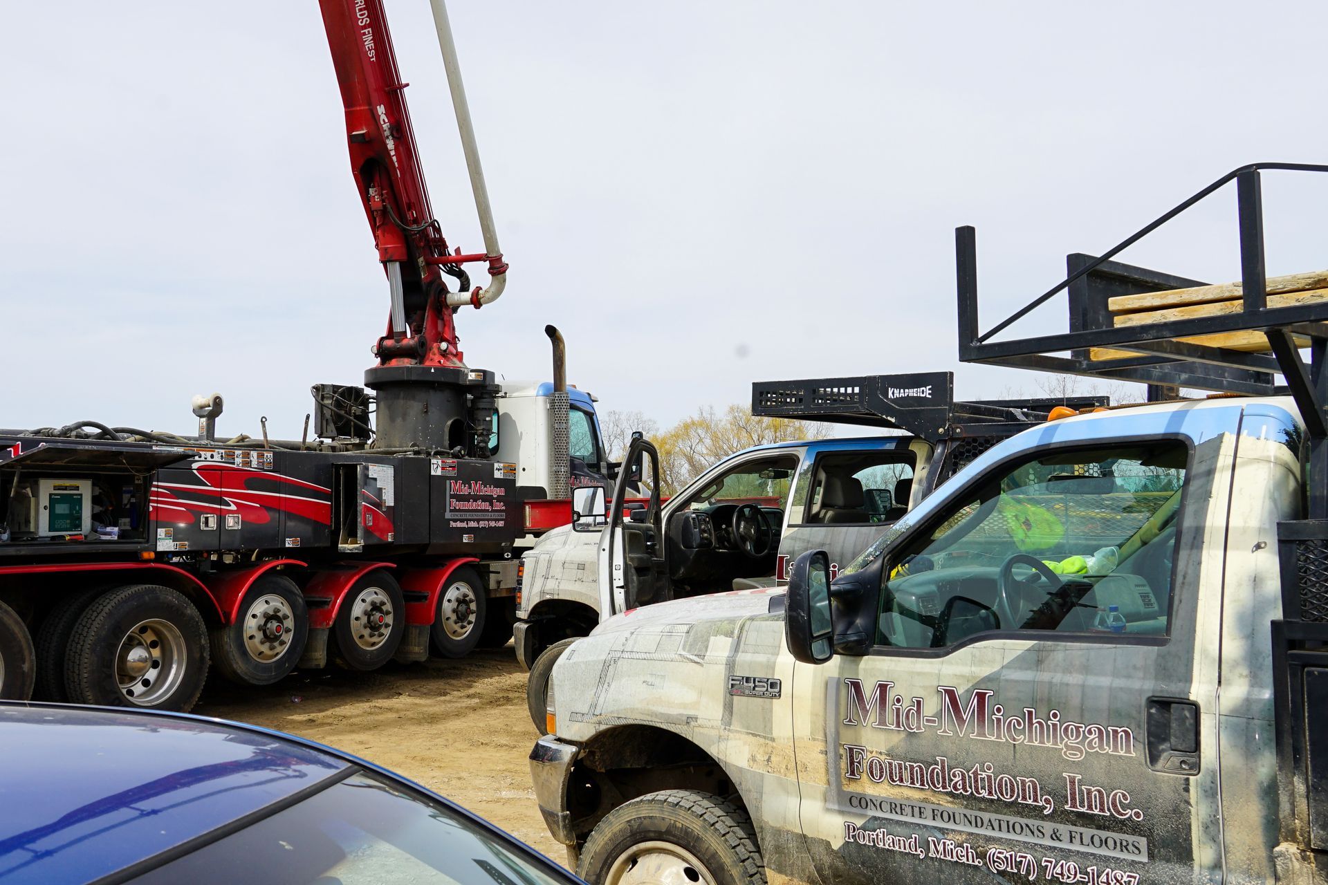 A couple of trucks are parked next to each other on a dirt road.