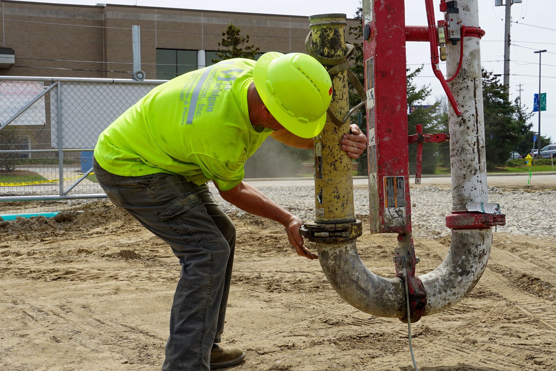 A man in a yellow hard hat is working on a pipe.
