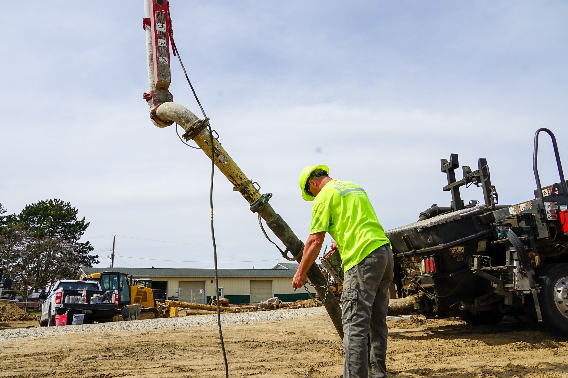 A construction worker is pumping concrete into a truck.