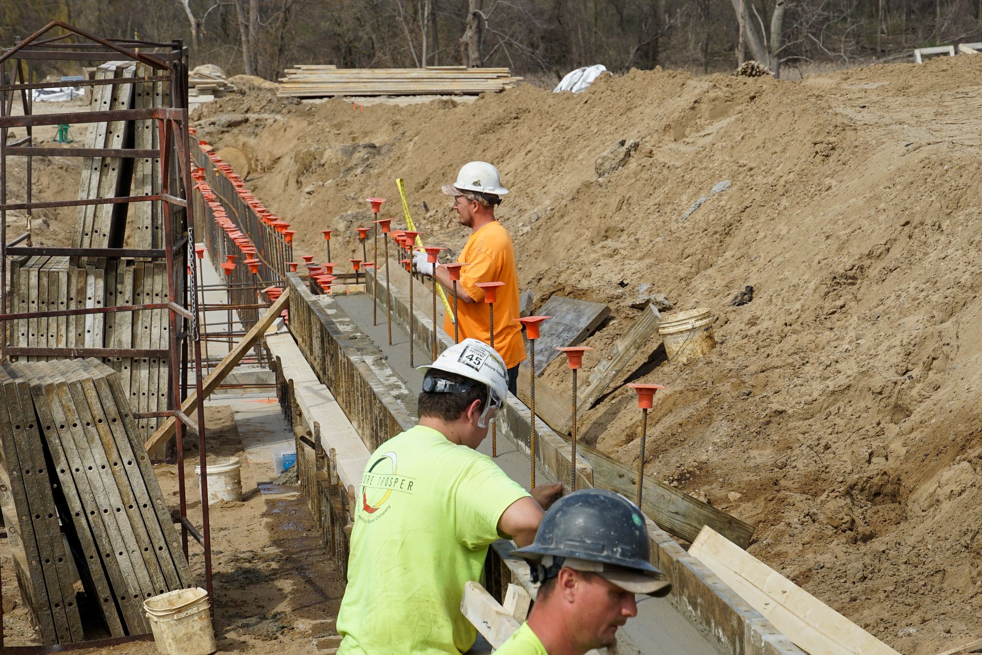 Two construction workers are working on a concrete wall