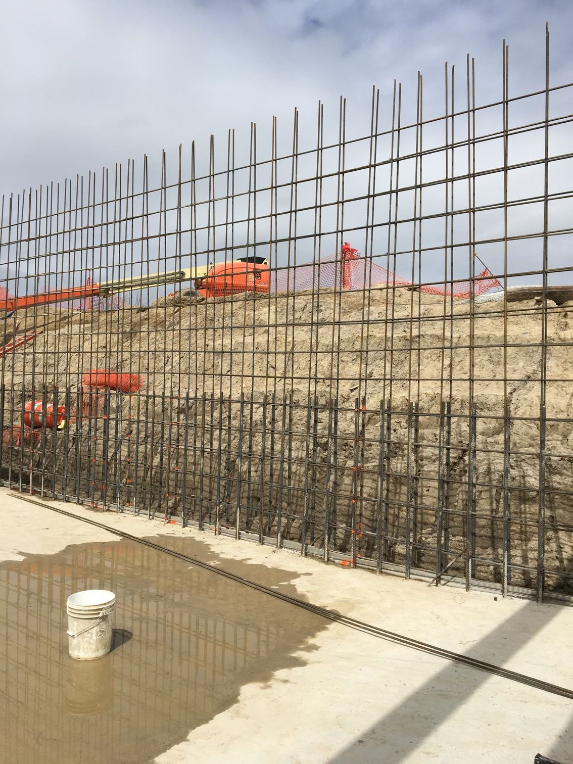 A bucket is sitting on the ground next to a fence.
