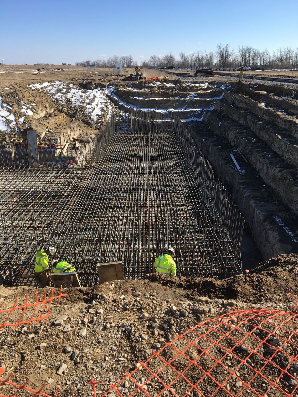 A group of construction workers are working on a large concrete structure.