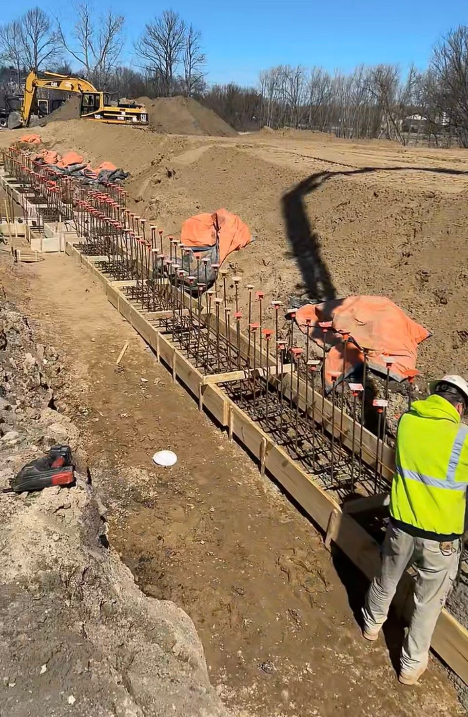 A man in a yellow jacket is working on a construction site.