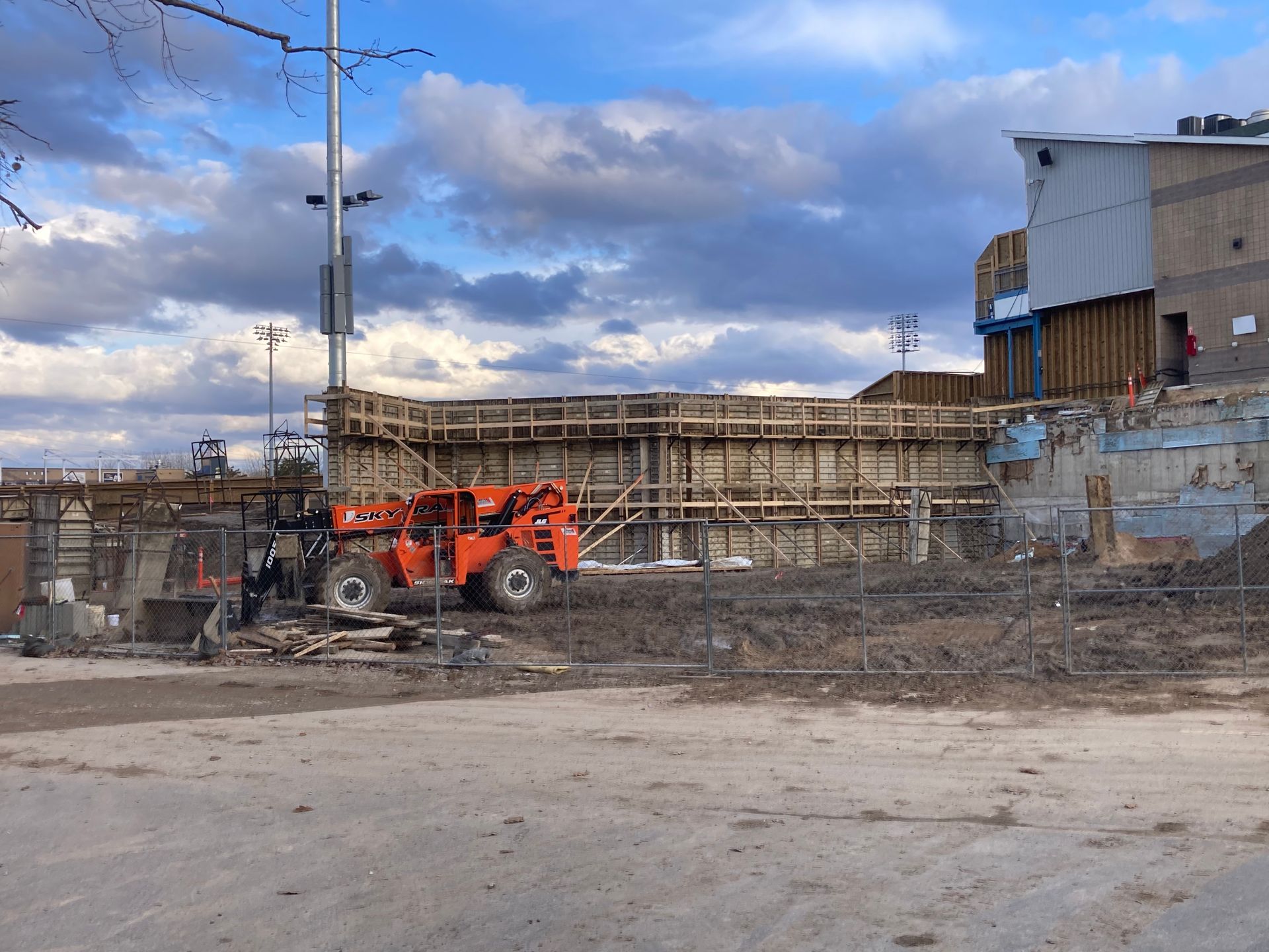 An orange forklift is parked in front of a building under construction.
